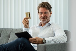 Man sitting on couch with credit card in hand